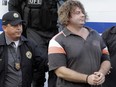 William Dathan Holbert is escorted by authorities upon his arrival in Panama City on July 29, 2010, after he was extradited from Nicaragua.