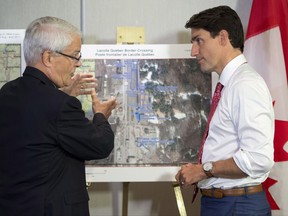 Prime Minister Justin Trudeau is briefed on the refugee installations at the Lacolle border crossing by Transportation Minister Marc Garneau prior to a meeting with the Intergovernmental Task Force on Irregular Migration, Wednesday, August 23, 2017 in Montreal. THE CANADIAN PRESS/Paul Chiasson