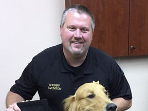 This photo provided by Yamhill County Sheriff's Office shows Yamhill County Sheriff Tim Svenson Posing for a photo as he honors the Avery family golden retriever, Kenyon, in McMinnville, Ore., Thursday, Aug. 17, 2017. Kenyon was honored for digging up $85,000 worth of black tar heroin in the family's backyard. (Yamhill County Sheriff's Office via AP)