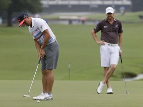 Rickie Fowler, left, putts as Jimmy Walker watches on the 18th hole during a practice round for the PGA Championship golf tournament at the Quail Hollow Club Tuesday, Aug. 8, 2017, in Charlotte, N.C. For the first time, the PGA Championship is letting players wear shorts in practice rounds. (AP Photo/Chris Carlson)