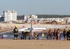 Firefighters stand next to a small plane after an emergency landing on Sao Joao beach that killed a 56-year-old man and an 8-year-old girl who were sunbathing in Costa da Caparica, outside Lisbon, Wednesday, Aug. 2, 2017.