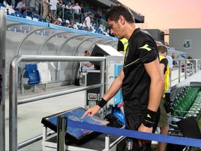 In this photo taken on Sunday, Aug. 20, 2017, referee Antonio Damato checks the VAR (video assistant referee) monitor prior to the Serie A soccer match between Genoa and Sassuolo at the Mapei Stadium in Reggio Emilia, Italy. The introduction of video review in Serie A was meant to eliminate controversial decisions. However, debate continues to rumble on after the first weekend using the new technology. (Elisabetta Baracchi/ANSA via AP)