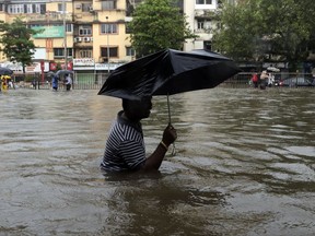 A man wades through a waterlogged street following heavy rains in Mumbai, India, Tuesday, Aug. 29, 2017. Heavy rains Tuesday brought Mumbai to a halt flooding vast areas of the city. (AP Photo/Rajanish Kakade)
