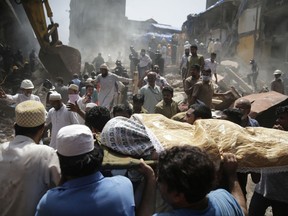 The body of a victim is carried out from the site of a building collapse in Mumbai, India, Thursday, Aug. 31, 2017. A five-story building collapsed Thursday in Mumbai, Indian's financial capital, after torrential rains lashed western India.