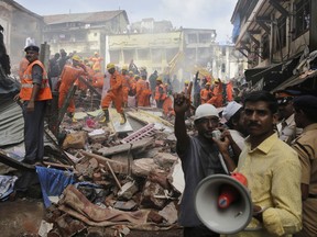 A rescue worker makes an announcement on a loudspeaker at the site of a building collapse in Mumbai, India, Thursday, Aug. 31, 2017. A five-story building collapsed Thursday in Mumbai, Indian's financial capital, after torrential rains lashed western India.