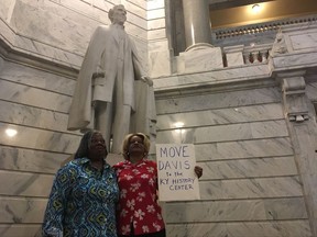 Charlene Holloway, right, and Gracie Lewis stand in front of a statue of Jefferson Davis in the Kentucky Capitol on Wednesday, Aug. 30, 2017. The women were some of the more than 100 people who attended a rally on calling for the statue's removal. Holloway says she is the descendant of a black slave and her white owner. (AP Photo/Adam Beam)
