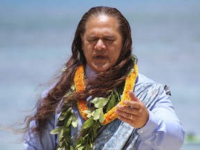 Rev. Elias Parker performs a blessing for a Hawaiian monk seal and her pup at a Waikiki beach in Honolulu on Tuesday, Aug. 8, 2017. State and federal authorities plan to move a newborn Hawaiian monk seal away from congested Waikiki so it can remain a wild animal and won't become accustomed to interacting with people. (AP Photo/Audrey McAvoy)