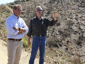 Yavapai County Supervisor Tom Thurman, right, talks with U.S. Sen. Jeff Flake as he points to an area where homes were saved during a June wildfire near Mayer, Ariz., Thursday, Aug. 10, 2017. Flake toured the area and then gave a speech to business leaders in nearby Prescott. (AP Photo/Bob Christie)