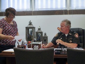 In this Aug. 9, 2017, photo, Lucas County Sheriff John Tharp speaks with his assistant Sandy Heban in his office in Toledo, Ohio. Police and rescue crews say drivers overdosing on heroin and other drugs are driving up the number of car crashes. Tharp says drivers in his county overdose on opioids so powerful it requires multiple doses of opiate antidote naloxone in order to revive them. (AP Photo/Danke Kang)