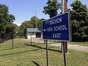A sign points to Sachem East High School in Farmingville, N.Y. where police say log fell on a teenage football player's head, killing him, Thursday Aug. 10, 2017. Joshua Mileto, 16, was participating in a pre-season drill with a group of high school football players, carrying a large log overhead for a workout, when the wood fell on his head. The 11th-grader was taken from the school to Stony Brook University Hospital, where he was pronounced dead. (AP Photo/Frank Eltman)