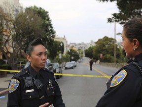 San Francisco Police Officer Grace Gatpandan speaks with another officer as they respond to reports of a shooting at Dolores Park in San Francisco on Thursday, Aug. 3, 2017. At least one gunman opened fire Thursday at the popular San Francisco park packed with families and tourists, leaving a few people wounded and sending dozens of panicked people running for cover, witnesses and police said. (AP Photo/Linda Wang)
