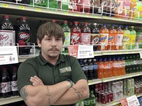 In this on Aug. 22, 2017 photo, Matt Gill, manager of Tischler Finer Foods in Brookfield, Ill., poses for a photo in the soda isle of the store. Gill says the new Cook County tax on sweetened beverages has reduced sales as customers go elsewhere to buy soda and other drinks. The tax also could carry a political price for county board President Toni Preckwinkle and others who voted for it. (AP Photo by Sara Burnett)