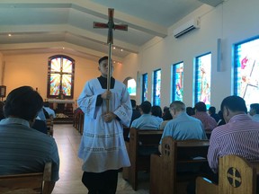 An altar boy carries a cross during Sunday Mass at Blessed Diego de San Vitores Church, Sunday, Aug. 13, 2017, in Tumon, Guam. Across Guam - where nearly everyone is Roman Catholic - priests are praying for peace as residents of the U.S. Pacific island territory face a missile threat from North Korea. (AP Photo/Tassanee Vejpongsa)