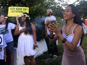 Eva Aguon Cruz, 30, holds a cup with burnt flower as a ritual to call for protections from the spirits as about a hundred people gathered at Chief Kepuha Park in Hagatna, Guam for a rally for peace Monday, Aug. 14, 2017.  Residents of Guam held a demonstration on Monday in support of peace.  The U.S. territory has been the subject of threats from North Korea in its escalating war of words with the U.S. President Donald Trump's administration. (AP Photo/Tassanee Vejpongsa)