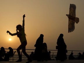 FILE- In this Saturday, April 8, 2017 file photo, a girl plays with her kite as visitors walk on the Red Sea beach, in Jiddah, Saudi Arabia. Saudi Arabia is planning to build a semi-autonomous luxury travel destination along its Red Sea coast that visitors can reach without a visa. The Red Sea area, which will include diving attractions and a nature reserve, will be developed with seed capital from the country's Public Investment Fund. (AP Photo/Amr Nabil, File)