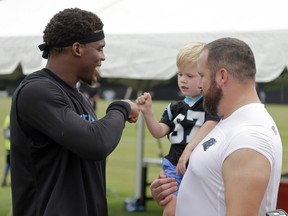 Carolina Panthers' Cam Newton, left, gives a fist bump to Cade Kalil, 3, son of Ryan Kalil, right, after practice at the NFL team's football training camp at Wofford College in Spartanburg, S.C., Wednesday, Aug. 2, 2017. (AP Photo/Chuck Burton)
