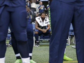 Seattle Seahawks defensive end Michael Bennett sits on the bench during the singing of the national anthem before an NFL football preseason game against the Minnesota Vikings, Friday, Aug. 18, 2017, in Seattle. (AP Photo/Stephen Brashear)