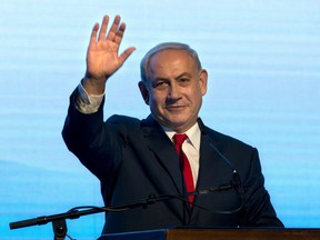 Israeli Prime Minister Benjamin Netanyahu waves during a rally of his Likud party supporters, near Tel Aviv, Israel, Wednesday, Aug. 30, 2017. Israeli Prime Minister Benjamin Netanyahu has lashed out at the "fake news industry" over media coverage of investigations into corruption allegations. (AP Photo/Sebastian Scheiner)