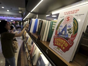 A copy of the Korean version of "Capitalist People's Republic of Korea", right, is displayed at Kyobo Book Store in Seoul, South Korea, Thursday, Aug. 31, 2017. North Korea on Thursday vowed to execute reporters from two South Korean newspapers, saying they insulted the country's dignity while reviewing and interviewing the British authors of a book about life in the isolated country. The signs read "Capitalist People's Republic of Korea." (AP Photo/Ahn Young-joon)