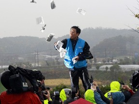 FILE - In this Oct. 22, 2012 file photo, Park Sang Hak, a refugee from the North Korea who now runs the group Fighters for a Free North Korea from a small Seoul office, hurls anti-North Korea leaflets as police block his planned rally on a road in Paju near demilitarized zone, South Korea. In South Korea, political activists send thousands of leaflets, DVDs and flash drives every year across the border into North Korea, mostly by balloon, hoping to bring to the isolated country. (AP Photo/Ahn Young-joon, File)