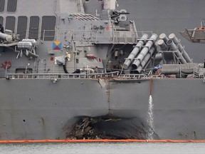 The damaged port aft hull of the USS John S. McCain, is visible while docked at Singapore's Changi naval base on Tuesday, Aug. 22, 2017 in Singapore. The focus of the search for the U.S. sailors missing after a collision between the USS John S. McCain and an oil tanker in Southeast Asian waters shifted Tuesday to the damaged destroyer's flooded compartments. (AP Photo/Wong Maye-E)