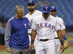 A Texas Rangers trainer walks with Adrian Beltre, right, to the dugout after he was injured fielding a ground ball bit by Houston Astros' J.D. Davis during the seventh inning of a baseball game Thursday, Aug. 31, 2017, in St. Petersburg, Fla. (AP Photo/Steve Nesius)