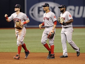 Boston Red Sox outfielders Andrew Benintendi, from left, Mookie Betts and Jackie Bradley Jr. head for the clubhouse after beating Tampa Bay Rays 8-2 during a baseball game Wednesday, Aug. 9, 2017, in St. Petersburg, Fla. (AP Photo/Steve Nesius)