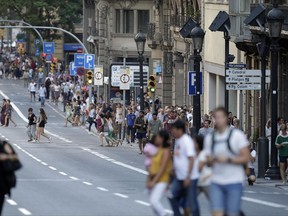People walk down a main street in Barcelona, Spain, Thursday, Aug. 17, 2017. Police in Barcelona say a white van has mounted a sidewalk, struck several people in the city's Las Ramblas district. (AP Photo/Manu Fernandez)