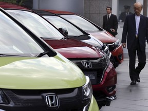 FILE - In this Friday, April 28, 2017, file photo, a man walks past Honda cars on display at Honda Motor Co. headquarters in Tokyo. Improved sales and cost cuts helped Japanese automaker Honda shrug off lingering troubles from the Takata air bag recalls to log a nearly 19 percent improvement in its fiscal first quarter profit. Tokyo-based Honda, which makes the Fit subcompact, Accord sedan and Asimo robot, on Tuesday, Aug. 1, reported a 207.3 billion yen ($1.9 billion) profit for April-June, up from 174.6 billion yen the same period last year. (AP Photo/Koji Sasahara, File)