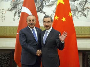 Chinese Foreign Minister Wang Yi, right, shakes hands with Turkish Foreign Minister Mevlut Cavusoglu during their meeting at Diaoyutai State Guesthouse in Beijing Thursday, Aug. 3 2017. (Roman Pilipey/Pool Photo via AP)