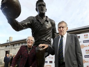 FILE - In this June 19, 2017 file photo, former All Black great, Sir Colin Meads, right, and his wife Vera pose for a photo with the statue of himself at the unveiling in Te Kuiti, New Zealand.  Meads, a famously tough All Blacks lock hailed New Zealand's greatest rugby player of the twentieth century, has died after a year-long battle with cancer. He was 81. Meads played 55 tests among 133 games for New Zealand between 1957 and 1971 - a number thought prodigious in an era in which the All Blacks seldom played more than four tests a year.(Alan Gibson/New Zealand Herald via AP, File)