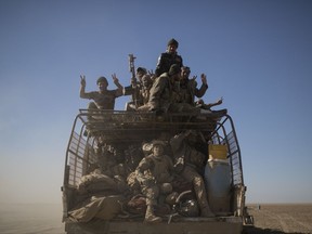 Popular Mobilization Units fighters ride on the back of a truck on their way to fight against Islamic State militants in the airport of Tal Afar, west of Mosul, Iraq. The operation to retake the town of Tal Afar, west of Mosul, from the Islamic State group began Sunday, Iraq's prime minister said.