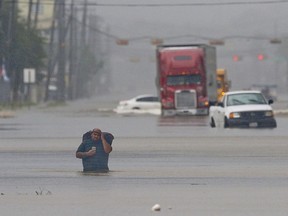 A man carries his belonging through the flood waters on Telephone Rd. in Houston on August 27, 2017.