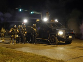 In this photo taken Aug. 18, 2014, police is riot gear work to disperse a crowd of protesters