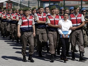 Paramilitary police and members of the special forces escort unidentified suspects of last year's failed coup, outside the courthouse at the start of a trial, in Ankara, Turkey, Tuesday, Aug. 1, 2017.