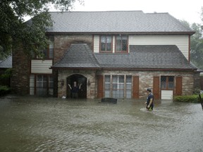 A man standing in the doorway of his flooded home responds to an evacuation offer in a neighborhood inundated by floodwaters from Tropical Storm Harvey on Monday, Aug. 28, 2017, in Houston, Texas. (AP Photo/Charlie Riedel)