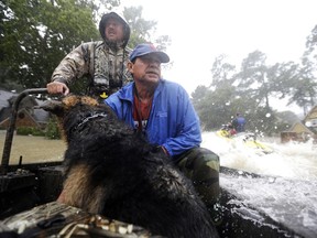Joe Garcia, right, and his dog Heidi ride in Murphy Fire Department's Todd Herrington's boat after being rescued from his flooded home as floodwaters from Tropical Storm Harvey rise Monday, Aug. 28, 2017, in Spring, Texas. (AP Photo/David J. Phillip)