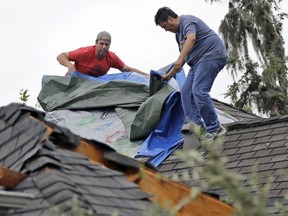 Roofers repair damage after a tornado from Hurricane Harvey Saturday, Aug. 26, 2017, in Missouri City, Texas.   Harvey rolled over the Texas Gulf Coast on Saturday, smashing homes and businesses and lashing the shore with wind and rain so intense that drivers were forced off the road because they could not see in front of them. (AP Photo/David J. Phillip)