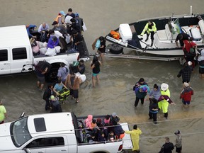 Evacuees are helped as floodwaters from Tropical Storm Harvey rise Tuesday, Aug. 29, 2017, in Houston.
