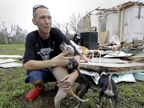 Sam Speights tries to hold back tears while holding his dogs and surveying the damage to his home in the wake of Hurricane Harvey, Sunday, Aug. 27, 2017, in Rockport, Texas. Speights tried to stay in his home during the storm but had to move to other shelter after he lost his roof and back wall. (AP Photo/Eric Gay)