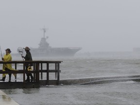 Fishermen walk along a pier as the early bands of Hurricane Harvey make landfall, Friday, Aug. 25, 2017, in Corpus Christi, Texas.