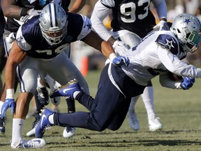 Tyrone Crawford tackles Ezekiel Elliott in football practice as the Dallas Cowboys hold training camp in Oxnard, Calif., Tuesday, Aug. 8, 2017. Crawford badly turned his left ankle making the tackle but there was no immediate word on the severity of the injury. Crawford has started 45 games at end and defensive tackle over the past three seasons since missing all of 2013 after tearing his left Achilles tendon in training camp. (Rodger Mallison/Star-Telegram via AP)