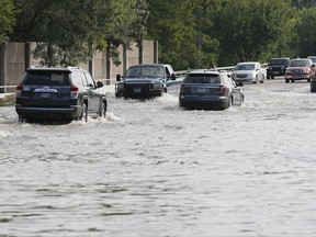 Vehicles drive through floodwaters in the aftermath of Harvey, in Friendswood, Texas on Wednesday, Aug. 30, 2017.  Gov. Greg Abbott said Wednesday that "the worst is not over" for southeastern Texas as widespread flooding continues.  (Kevin M. Cox/The Galveston County Daily News via AP)