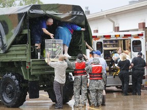 Evacuees are helped out of a high water rescue vehicle at Clear Creek ISD's Bauerschlag Elementary School in League City, Texas, Sunday, Aug. 27, 2017. (Kevin M. Cox/The Galveston County Daily News via AP)