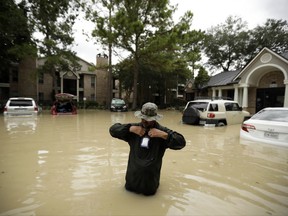 Patrick Tobias seals his phone in a bag after taking a picture of his flooded car, behind, as he stands in floodwater from Tropical Storm Harvey Wednesday, Aug. 30, 2017, in Kingwood, Texas. (AP Photo/Gregory Bull)