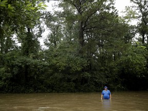 A man stands in floodwaters from Tropical Storm Harvey as he waits to board a boat to help look for evacuees Tuesday, Aug. 29, 2017, in Kingwood, Texas. (AP Photo/Gregory Bull)