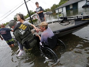 Members of the Louisiana Department of Wildlife and Fisheries help rescue Mike Henry, right, and his partner Rosemarie Carpenter during flooding from Tropical Storm Harvey in Orange, Texas, Wednesday, Aug. 30, 2017. (AP Photo/Gerald Herbert)