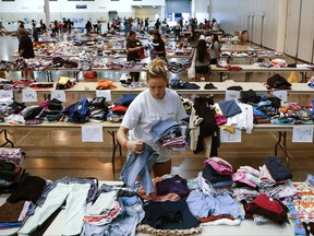 Volunteer Paige Atkinson sorts donated clothing at NRG Center, which opened its doors to  evacuees in the wake of Tropical Storm Harvey Wednesday, Aug. 30, 2017 in Houston. Officials say nearly all Houston-area waterways inundated by Harvey's record rainfall have crested, but that water levels continue to rise in two flood-control reservoirs. (Michael Ciaglo /Houston Chronicle via AP)