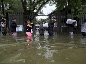 Residents from Bayou Parc at Oak Forest carry their belongings while evacuating the apartment complex during the Tropical Storm Harvey, Sunday, Aug. 27, 2017, in Houston.  The remnants of Hurricane Harvey sent devastating floods pouring into Houston Sunday as rising water chased thousands of people to rooftops or higher ground. (Marie D. De Jesus/Houston Chronicle via AP)