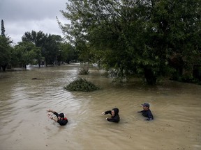 People wade through chest deep water down Pine Cliff Drive as Addicks Reservoir nears capacity due to near constant rain from Tropical Storm Harvey Tuesday, Aug. 29, 2017 in Houston. ( Michael Ciaglo/Houston Chronicle via AP)